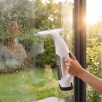 Lavavetri elettrico Vitropole che aspira l'acqua da una vetrata, vetro nitido dopo la passata